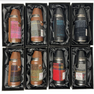 alt= a collection of hunting flasks with two different styles of leather brown and black and eight different harris tweed patterns on a white background