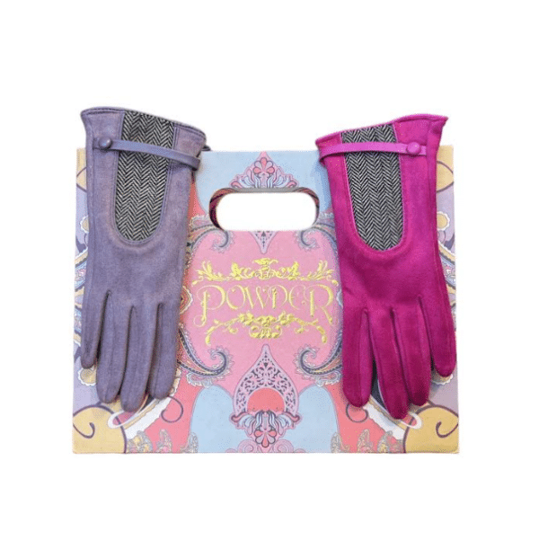 alt= a pair of gloves one pink the other purple resting on a bag with a colorful design
