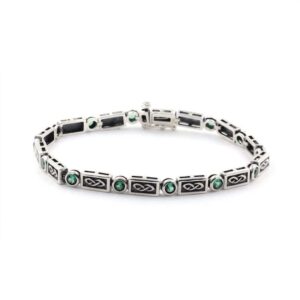 Irish silver tennis bracelet with emerald-green stones, Claddagh and Celtic knotwork motifs; symbolizing love and heritage.