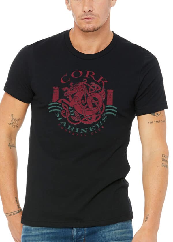 Irish man in black tee with vivid red Cork Mariners FC crest; Celtic knot tattoos on arms evoke rich Irish heritage.