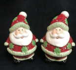 Two Irish ceramic Santa shakers, adorned with red outfits and hand-painted green Celtic holly, evoke festive heritage charm.