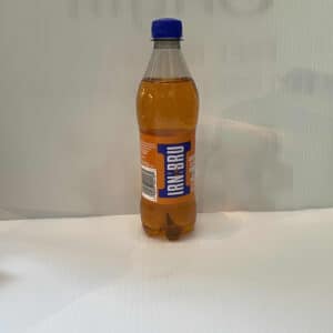 Scottish Irn-Bru bottle with vibrant orange soda, blue cap, and iconic thistle-branded label on a crisp white surface.