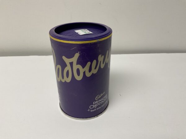 Certainly! Here’s a modified alt text according to your criteria: Rich purple Cadbury Hot Chocolate tin featuring British heritage design, gold accents, and crafted for warming traditional drinks.