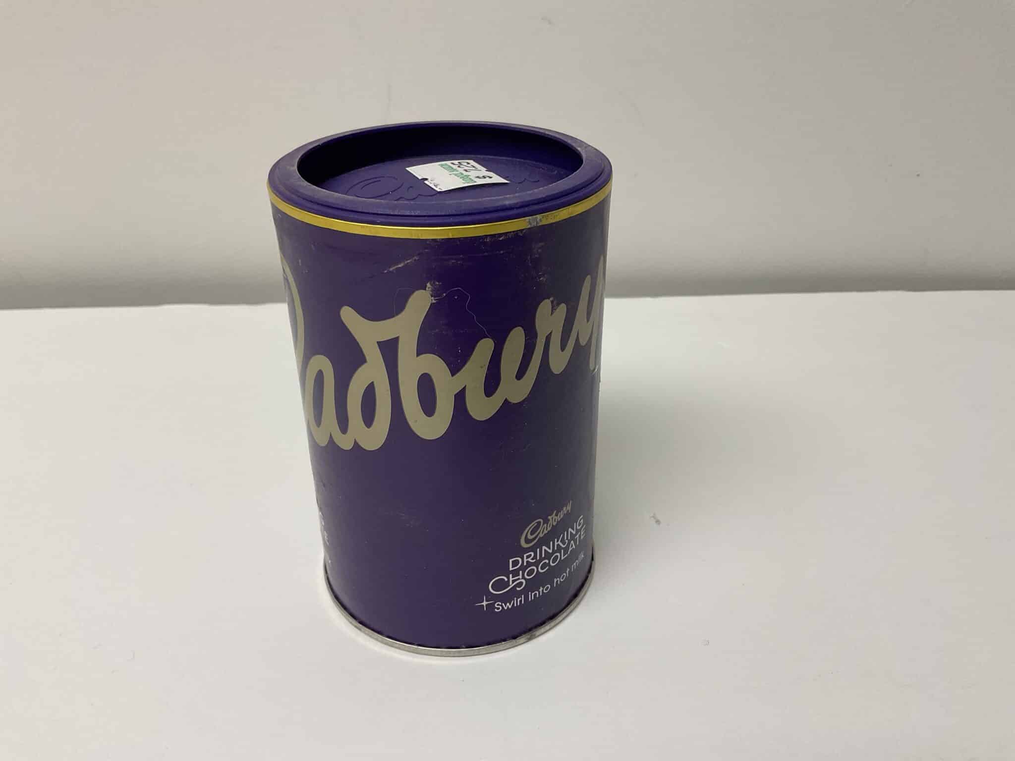 Certainly! Here’s a modified alt text according to your criteria: Rich purple Cadbury Hot Chocolate tin featuring British heritage design, gold accents, and crafted for warming traditional drinks.