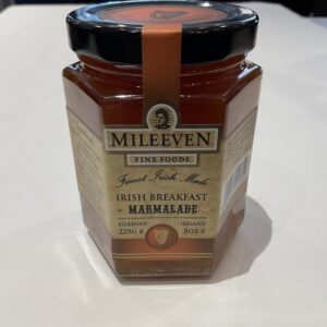 A jar of Irish Mileeven Breakfast Marmalade 225g with Celtic knot motifs, black lid, and amber-orange preserve on white surface.