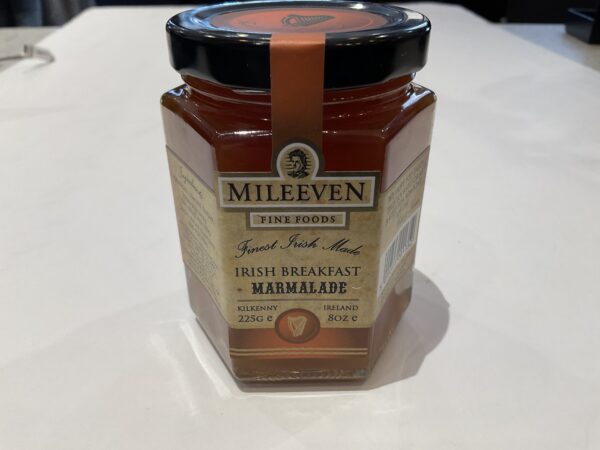A jar of Irish Mileeven Breakfast Marmalade 225g with Celtic knot motifs, black lid, and amber-orange preserve on white surface.
