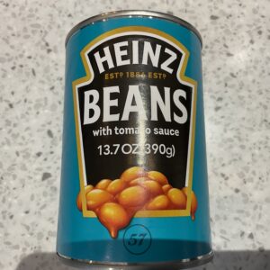 Sure! Here’s an improved alt text based on your guidelines: Irish Heinz Baked Beans can, blue-green label with gold trim, classic design atop speckled stone countertop—hearty staple.