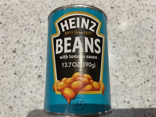 Sure! Here’s an improved alt text based on your guidelines: Irish Heinz Baked Beans can, blue-green label with gold trim, classic design atop speckled stone countertop—hearty staple.